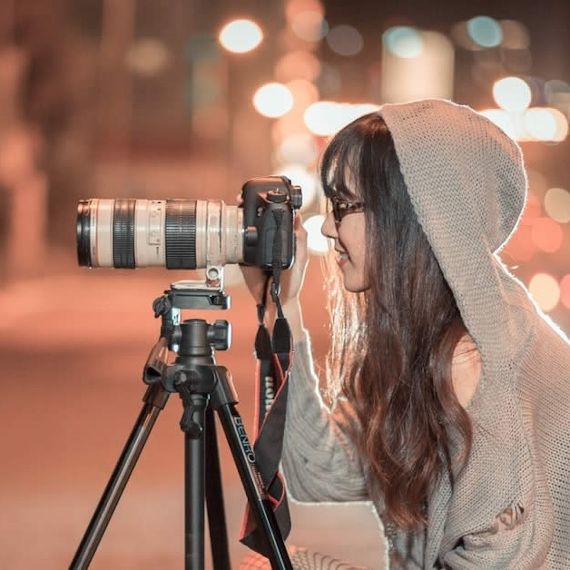 une fille prenant des photos dans la rue avec un appareil photo avec un trépied